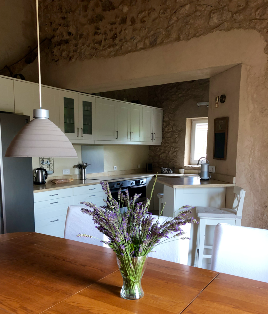 table de salle a manger avec bouquet de lavandes et cuisine intégrée en arrière plan